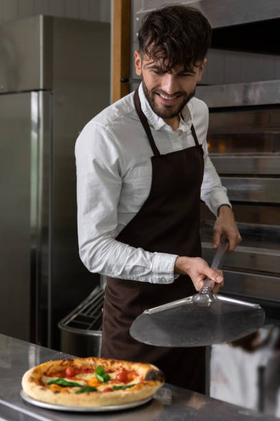 istock Smiling cooker preparing tasty pizza in pizzeria 1931090821