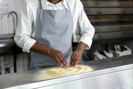 African american young woman preparing pizza in the kitchen