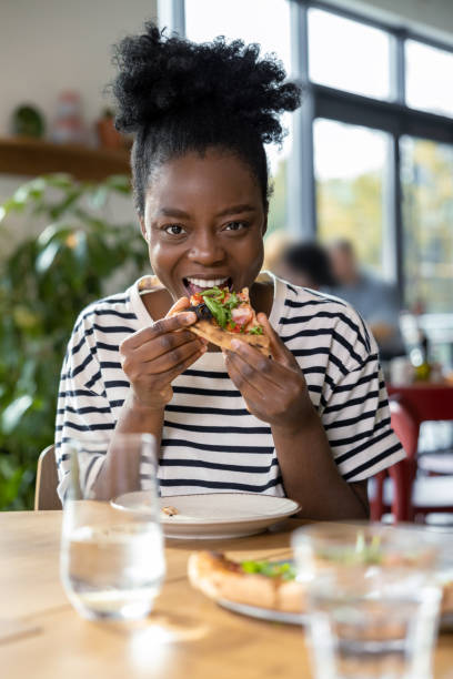 istock Cute dark-skinned young woman enjoying pizza 1931091392