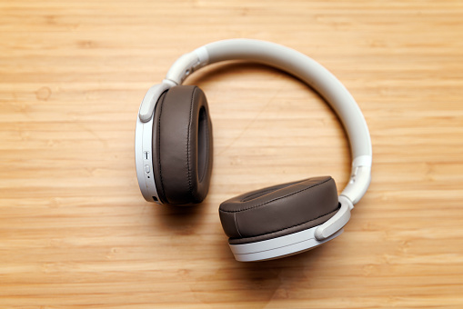 The pair of wireless headphones on a wooden surface.