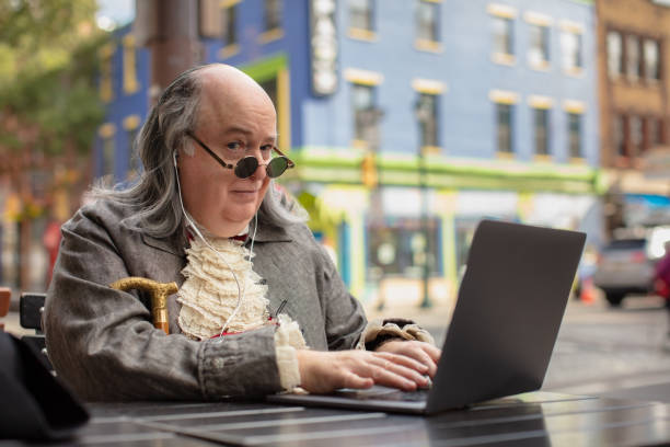 sobowtór benjamina franklina piszący na swoim laptopie, patrząc na kamerę z uniesioną brwią - benjamin franklin history american culture portrait zdjęcia i obrazy z banku zdjęć