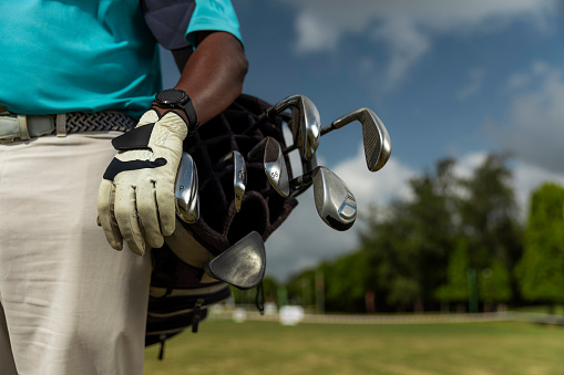 Golfer carrying golf clubs in a golf bag