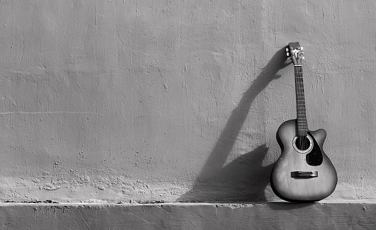 Old wall background with guitar decoration in the corner. Photo in black and white. Suitable as a background image for various design needs, quotes, posters, etc.