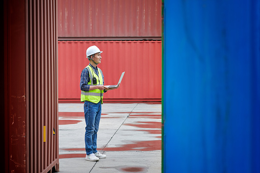 One asian male warehouse examining cargo container in commercial dock.