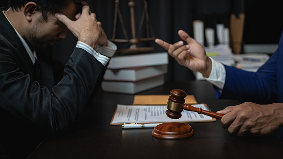 A lawyer is meeting with a new client, a young man in a suit and tie sits at the table. Share legal advice Explain the inheritance process Legal and financial business concepts