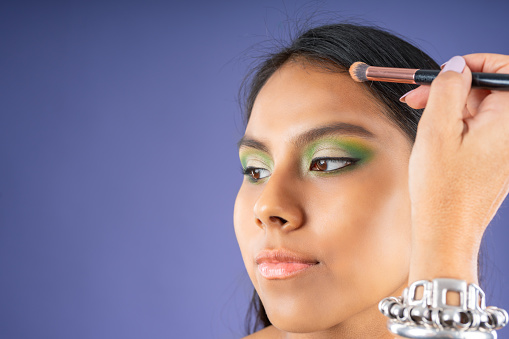 Young woman in a make-up session, on a purple background.