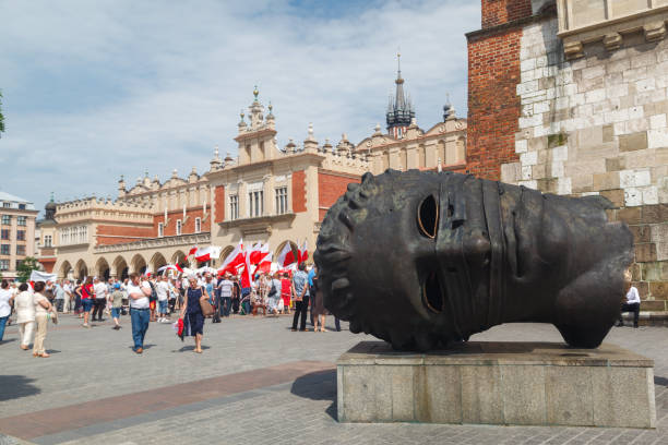 A head sculpture and the historical buildings at the market square, Krakow, Poland