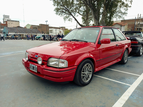 Lanús, Argentina - Sept 25, 2022: Old red shiny 1980s Ford Escort MK IV at a classic car show in a park.