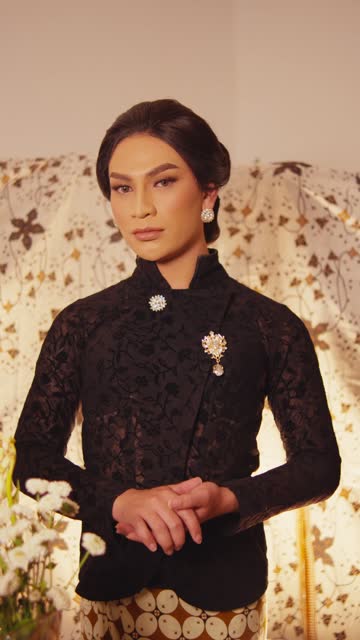 Elegant woman in vintage attire posing against floral backdrop.