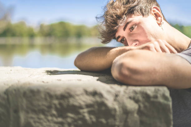 Young man falls his head down on his arms in a park