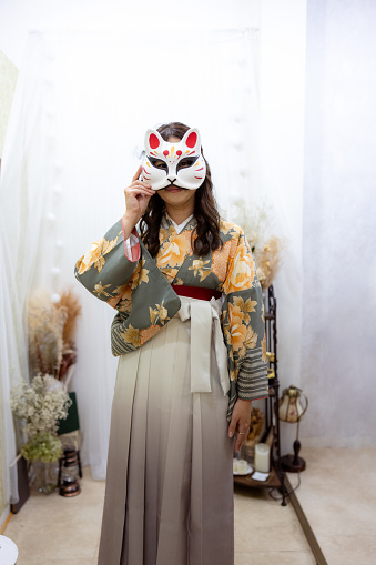 Portrait of Female tourist in Kimono / Hakama wearing a fox mask