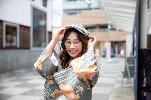 Portrait of female tourist in Kimono / Hakama wearing beret on street