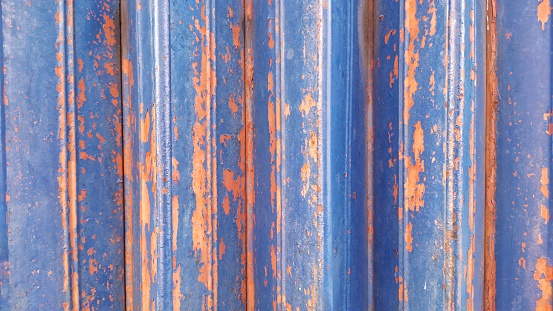 Iron door of shophouse with blue and orange color that peeled off. Textured and background. Obsolete