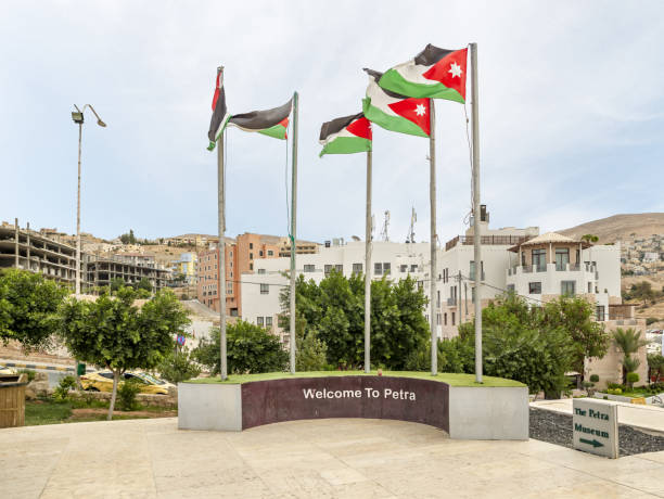 pocas banderas jordanas ondean en altos mástiles cerca de la entrada del centro turístico de petra en la ciudad de wadi musa en jordania - siq al barid fotografías e imágenes de stock