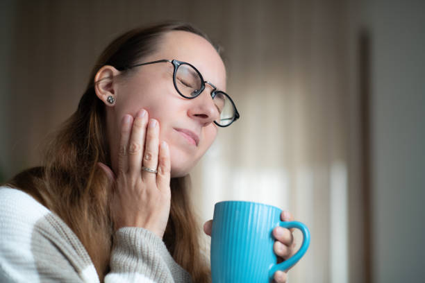 Woman with a cup of  hot tea suffering from tooth sensitivity