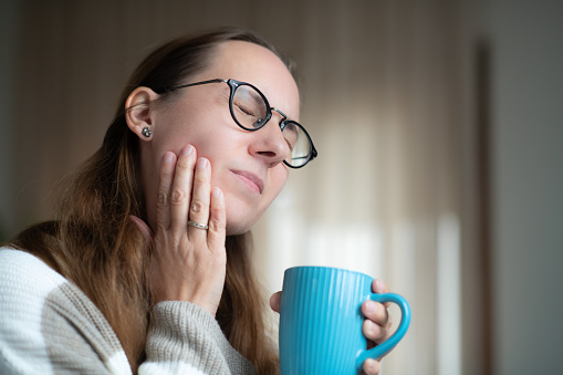 Woman with hot tea suffering from tooth sensitivity