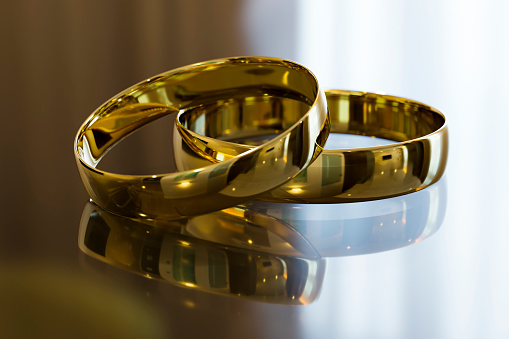Two beautiful gold wedding rings on a mirror surface close-up.