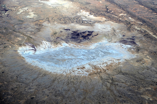 Aerial view of a isolated salt flat the vast Kati Thanda–Lake Eyre, an endorheic salt lake basin in the east-central part of the Far North region of South Australia. The lake contains the lowest natural point in Australia, at approximately 15 m below sea level.