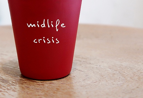Red cup on table with text on the side MIDLIFE CRISIS, concept of emotional crisis of identity and self-confidence that occur in early middle age - period of emotional turmoil in midlife