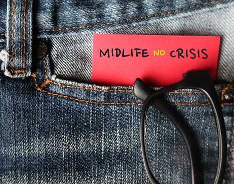 Reading glasses in jeans pocket with handwritten text on note MIDLIFE NO CRISIS - to overcome crisis on transition of identity and self-confidence usually occur in middle-aged 45 to 65 years old