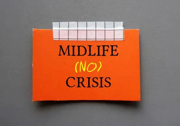 Photo of Red card stick on wall with handwritten text MIDLIFE NO CRISIS - to overcome crisis on transition of identity and self-confidence usually occur in middle-aged 45 to 65 years old
