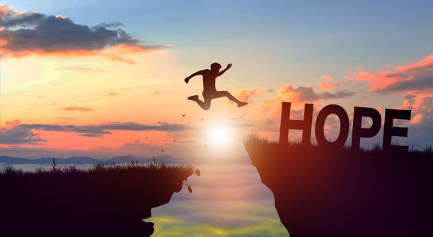 istock Silhouette man jumping form cliff to another mountain with Hope. 1931594443