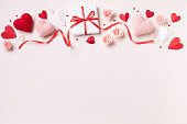 Valentine day or mother day festive composition with gift or present box, rose flowers and red pink hearts on pastel background top view.