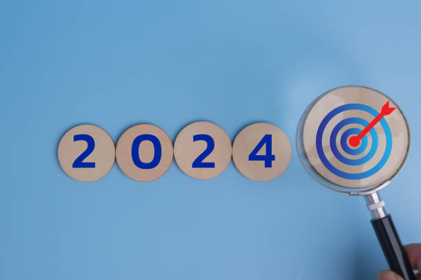 istock hand hold magnifier vision new year 2024 on background. Concept strategy target plan and goal finance investment and management 1931633810