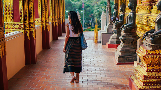 Portrait of Young beautiful Asian woman wearing Thai traditional country style dress posting at ancient temple with old pagoda. Beautiful Thai girl in Thai traditional costume.