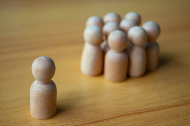 istock A single wooden doll separated by other dolls. Representing either leadership or isolation. 1931664517