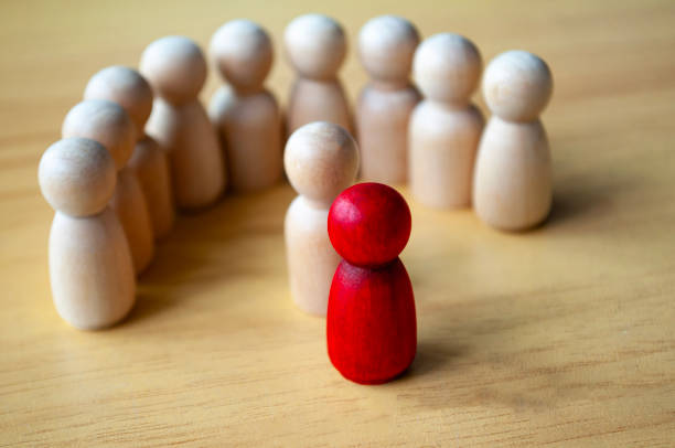 istock Red wooden doll surrounded with other dolls. Representing either leadership or harassment. 1931664528
