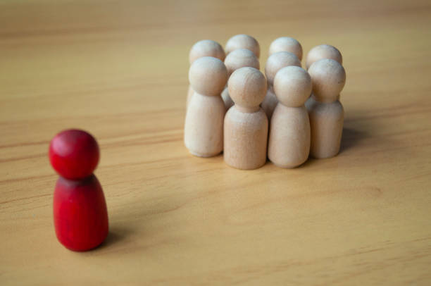istock Red wooden doll separated by other dolls. Representing either leadership or isolation 1931666328