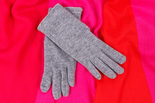 Pair of gray warm womanly woolen gloves and colorful shawl for using in autumn or winter