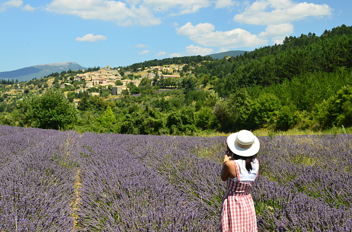 A rear shot of a woman contemplating a typical French south east village in the middle of a lavender field