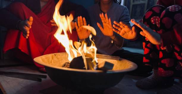 People warming hands while sitting around a bonfire in winter at home.