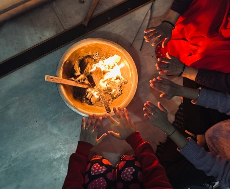 Group of people gathering around a bonfire and warming hands in cold winters at home.