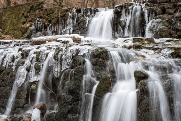 istock Icicles hang from the side of a waterfall, creating a stunning winter scene. The waterfall is located in a mountainous area, and the rocks are covered in ice. 1931771756