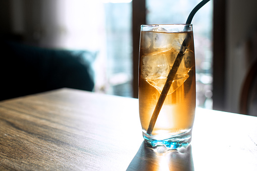 Ice tea or soda with ice cubes and drinking straw indoors