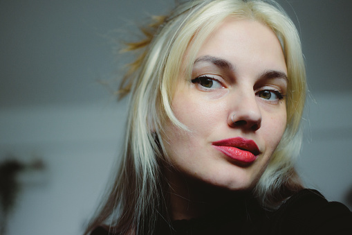 A beautiful blonde woman with flowing, lustrous hair and a vibrant shade of red lipstick strikes a confident pose