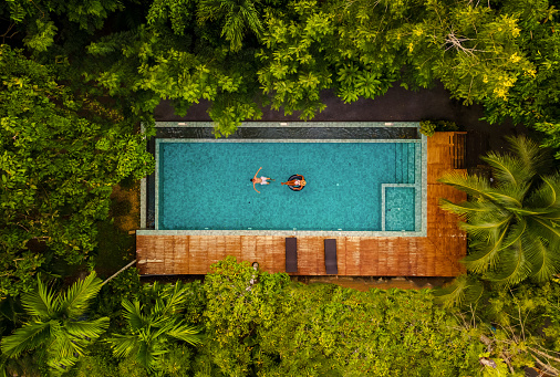 aerial drone view of swimming pool in the jungle of Krabi Thailand, aerial view with a drone above a swimming pool in the rainforest of Thailand. couple of men and women in pool during vacation