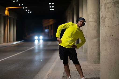 View of young man doing sports on the street at night in the city