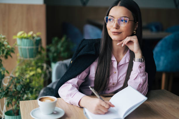 istock Young businesswoman writing notes in cafe 1931900370
