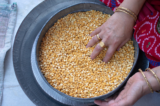 Picture of hand of an Indian woman cleaning dal (lentil). Gold, hand, fingers, cleaning, healthy, protein, rice, chapati, vegetables, strainer, bangles, Indian, festive, custom, tradition, culture.