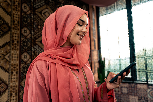 Beautiful young woman wearing colored abaya indoor in an arabian traditional cafe