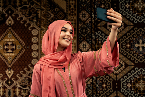 Beautiful young woman wearing colored abaya indoor in an arabian traditional cafe