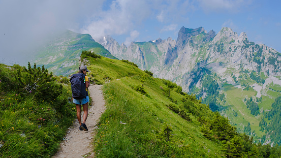 Asian women hiking in the Swiss Alps mountains during summer vacation with a backpack and hiking boots. woman walking on the Saxer Lucke path in Switzerland during summer