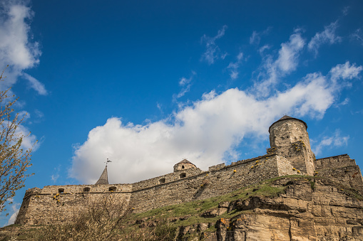 Old Kamianets-Podilskyi Castle under the blue sky. Part of the powerful bastions of the castle. The fortress located among the picturesque nature in the historic city of Kamianets-Podilskyi, Ukraine