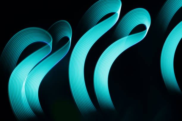 istock Turquoise blue glowing neon wave of light as curls or swirl with smooth stripes on black background, pattern. Abstract background with motion light effect in hipster style. 1931929384