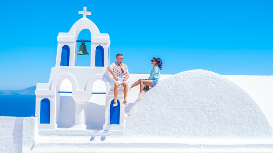 A couple watching the sunset on vacation in Santorini Greece, men and women visit the Greek village of Oia Santorini.