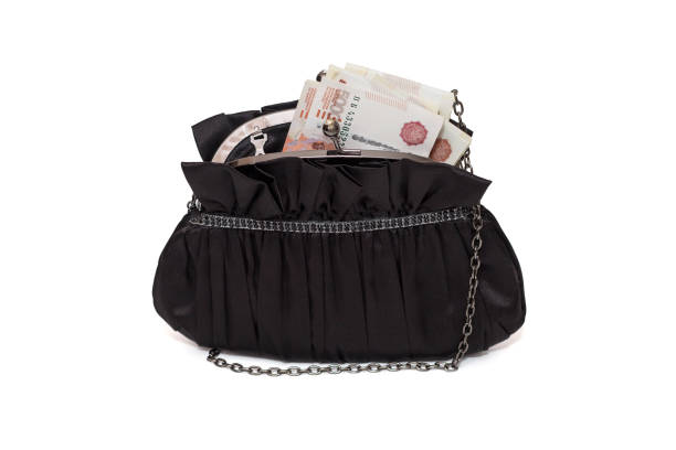 Women's evening handbag in black with bundles of money, isolated on white